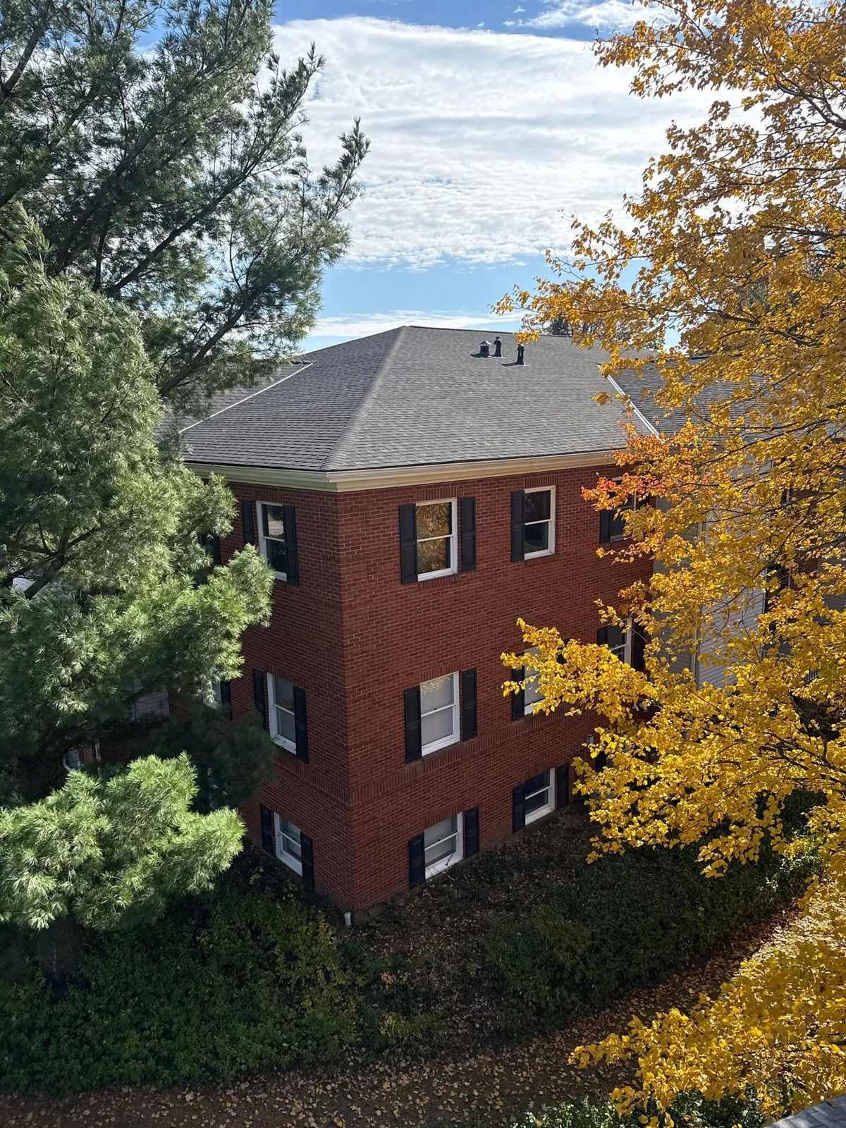 Brick office building with a new Owens Corning Williamsburg Gray hip roof framed by fall trees in Akron, Ohio