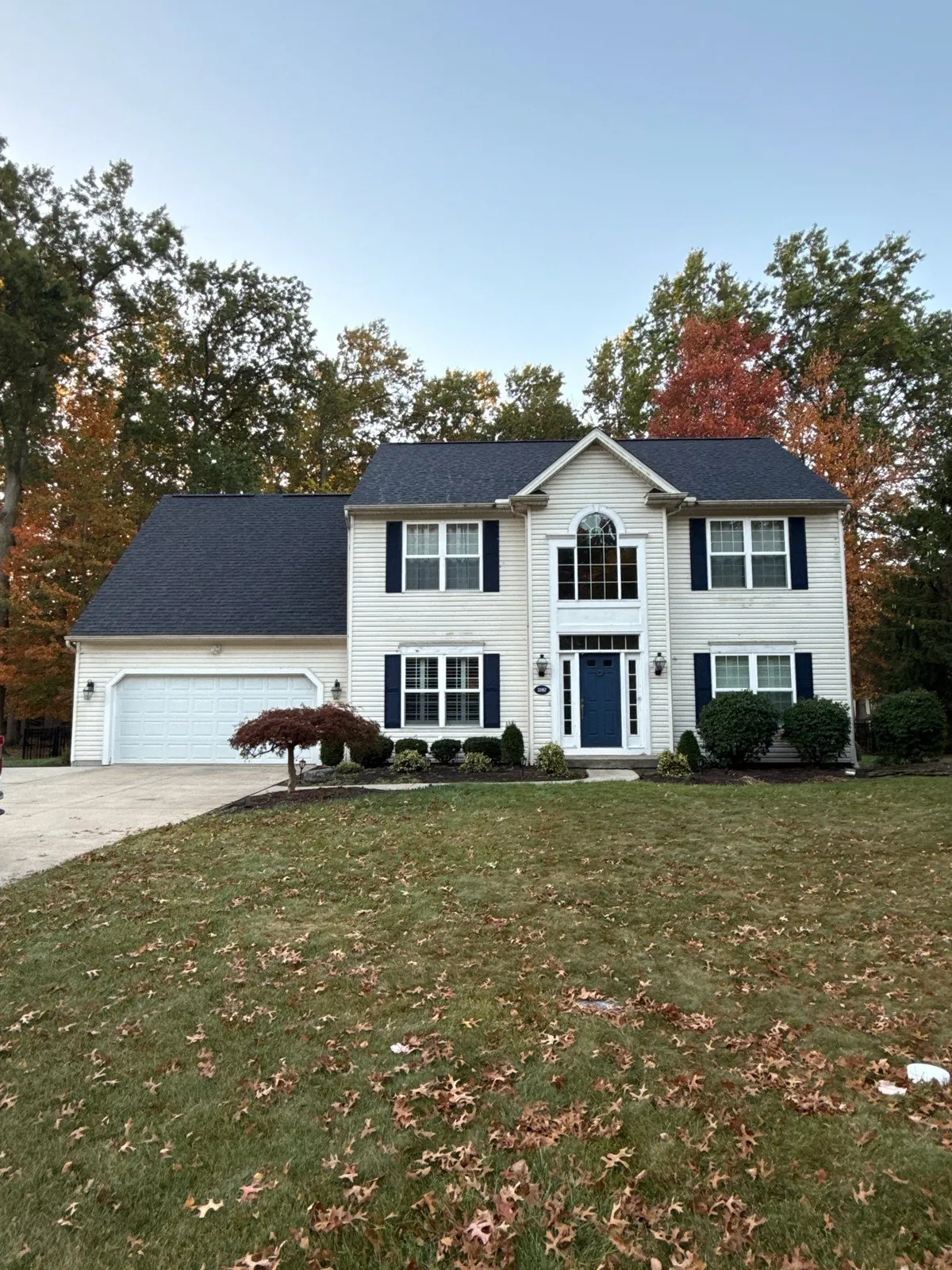 White two-story colonial with navy shutters, a two-car garage, and a new dark shingle roof in Avon Lake, Ohio