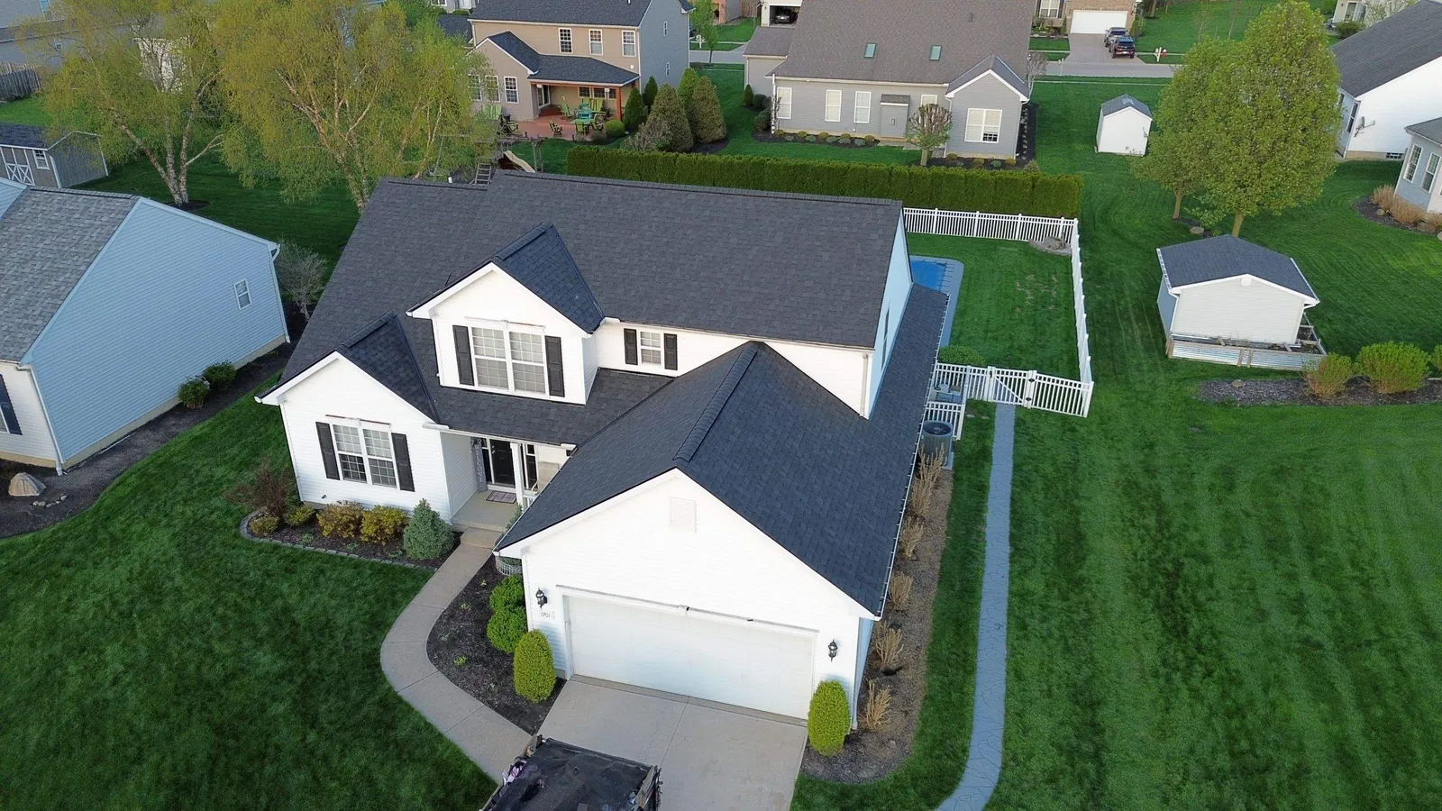 Drone view of a white two-story home with an attached garage and a new Owens Corning Onyx Black shingle roof in Avon, Ohio