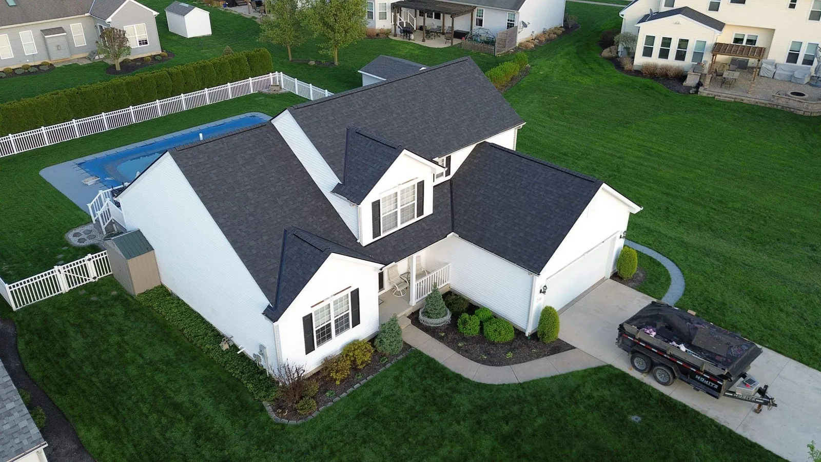 Aerial view of a white Avon, Ohio home with a backyard pool and a new Owens Corning Onyx Black roof over multiple gables