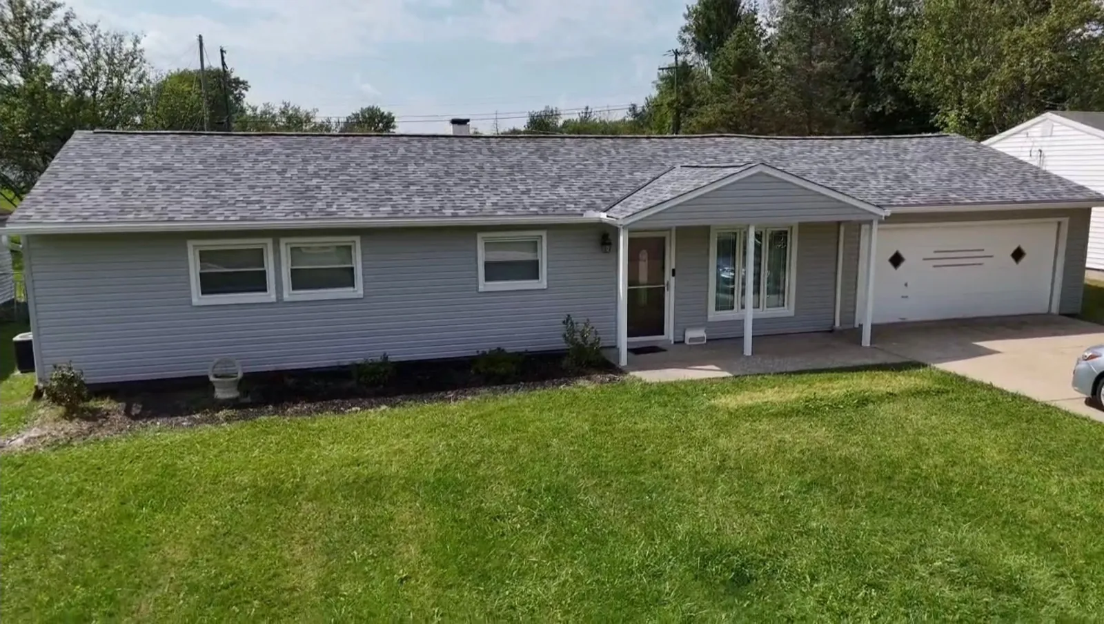 Ranch home with light gray siding, a covered front entry with white posts, and an attached garage in Bedford Heights, Ohio, with a new Owens Corning Duration Pacific Wave roof
