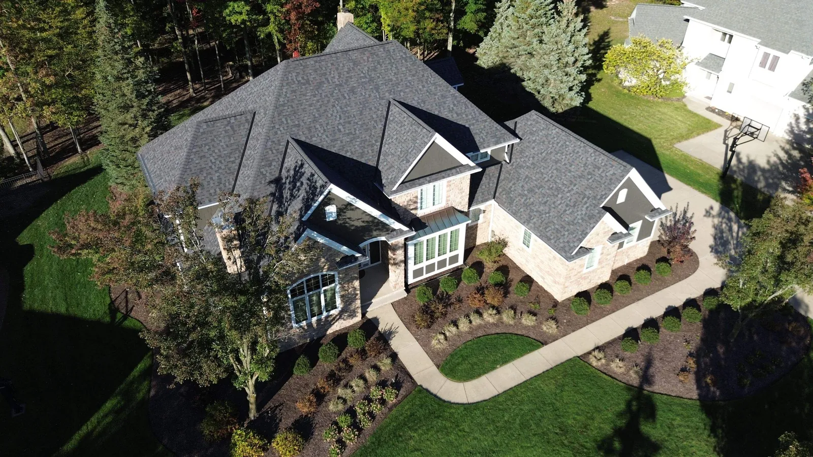 Aerial view of the front of a large stone and siding home in Brecksville, Ohio with a new Owens Corning Duration Williamsburg Gray roof and curved front walk