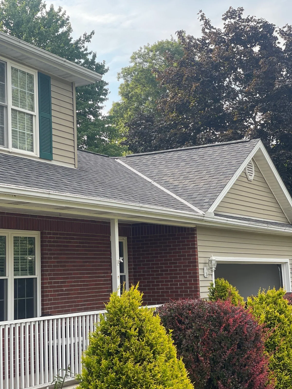 Close view of new gray shingles over the front porch and garage gable of a brick home in Broadview Heights, Ohio