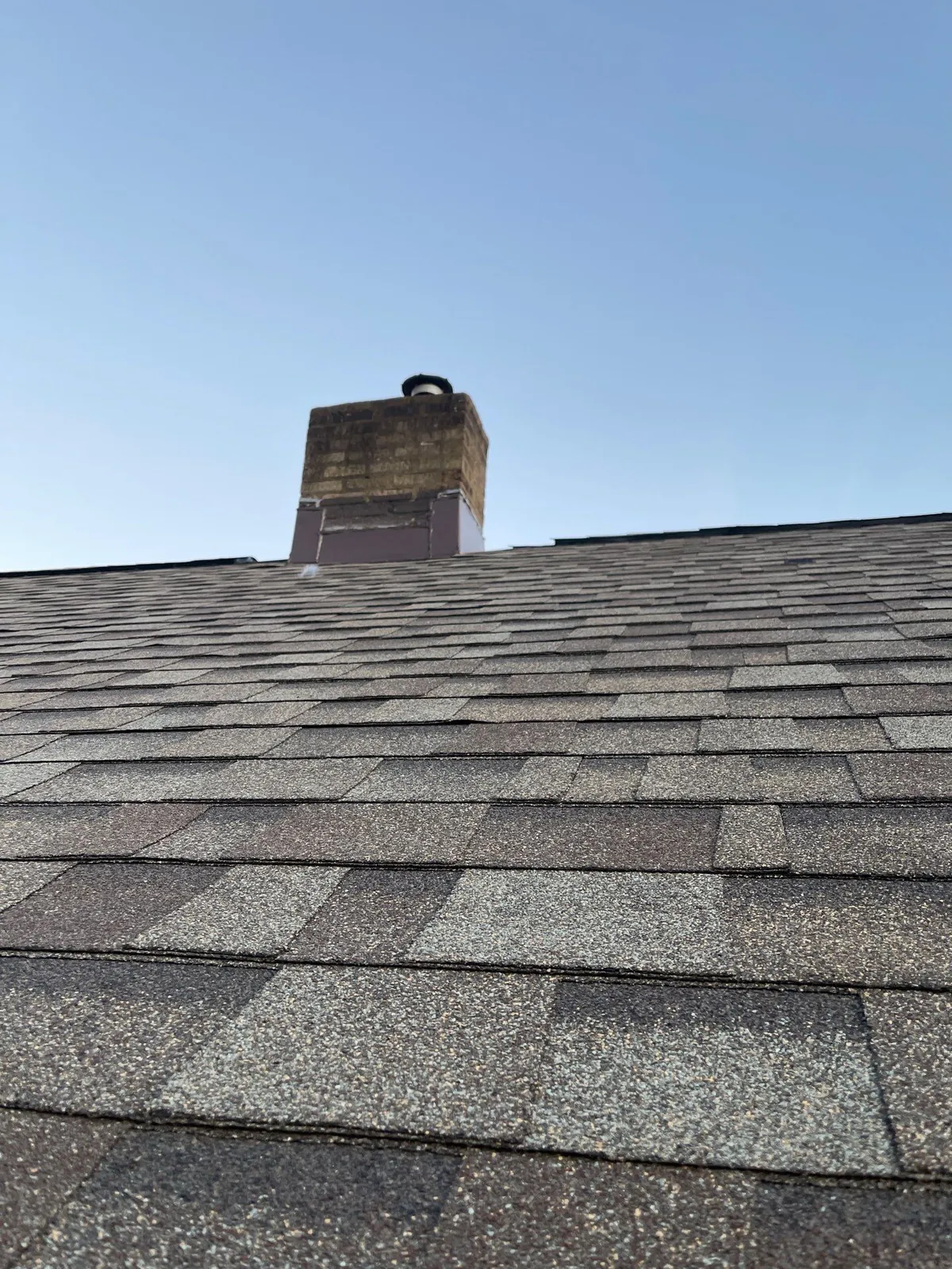 Close-up of new architectural shingles leading up to a brick chimney on a home in Cleveland's Kamm's Corners neighborhood