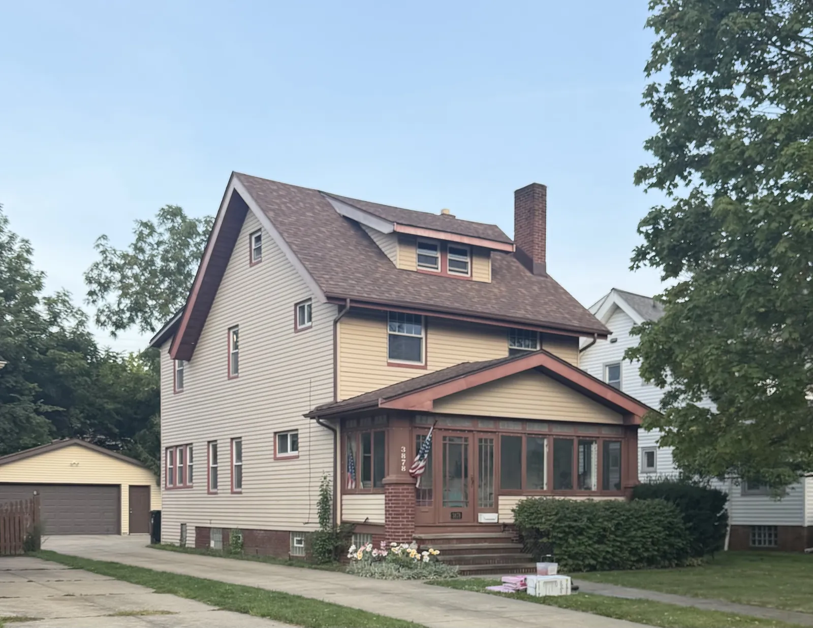 Two-and-a-half-story home with cream siding, an enclosed front porch, and a detached garage in Cleveland's West Park neighborhood, with a new Owens Corning Duration Desert Rose roof
