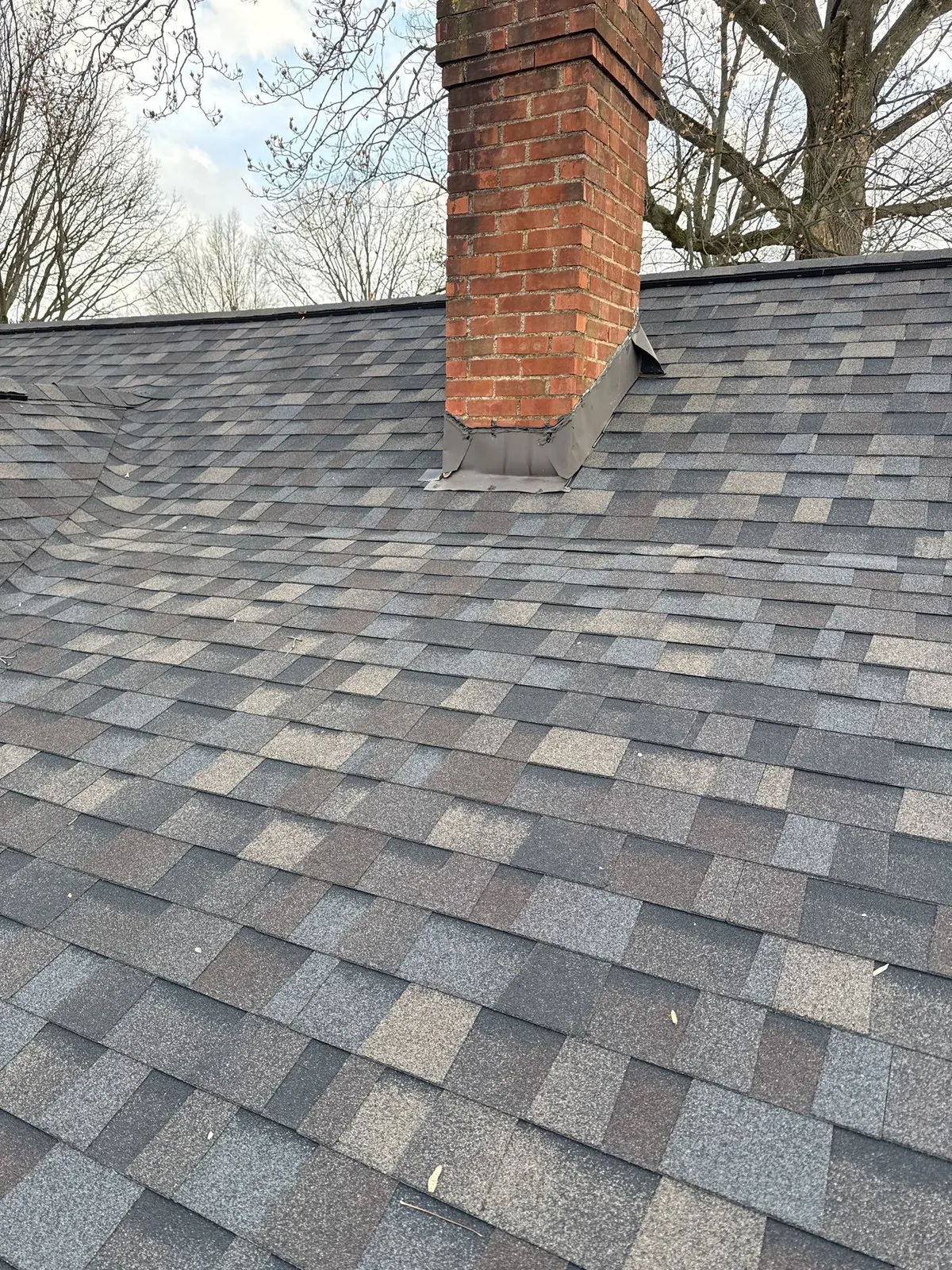 New chimney flashing around a brick chimney on a new shingle roof in Fairview Park, Ohio