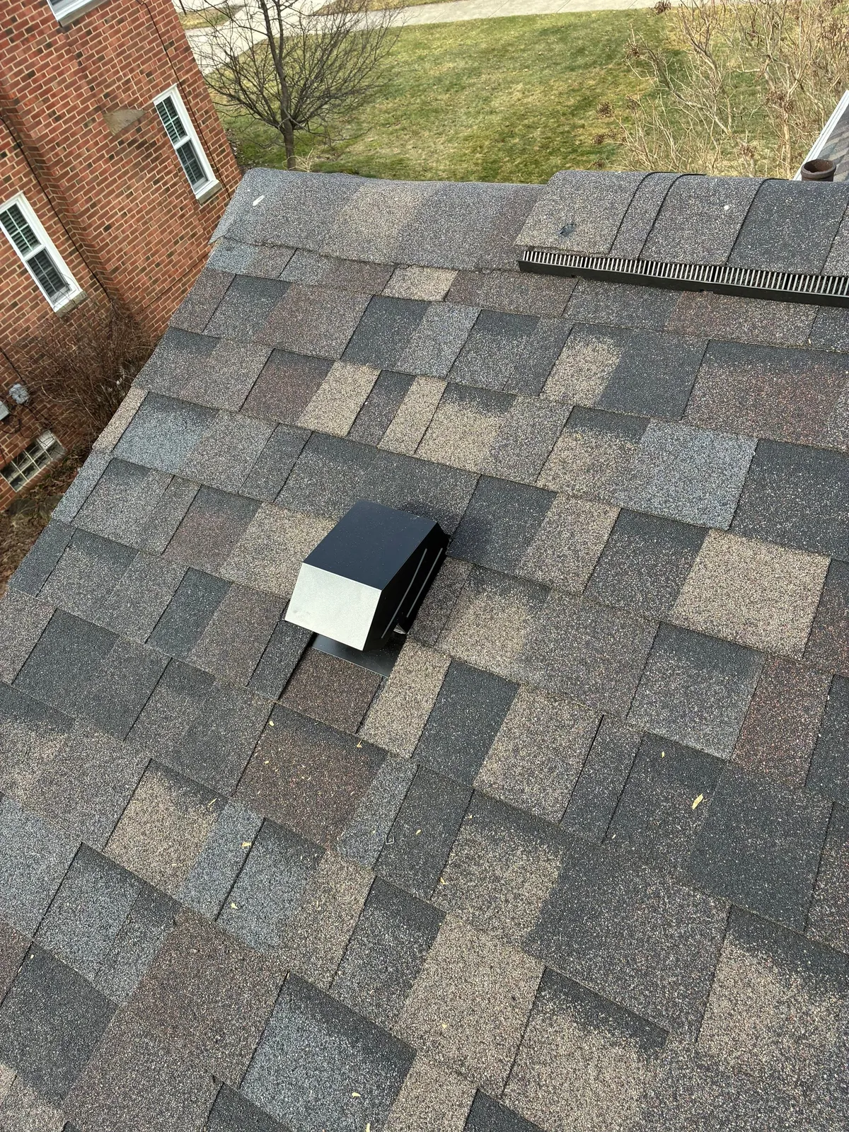 Repaired shingle roof section with a new roof vent on a brick home in Fairview Park, Ohio
