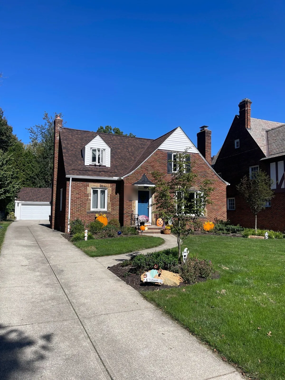 Red brick story-and-a-half home with a front dormer, two chimneys, and a new brown shingle roof in Fairview Park, Ohio