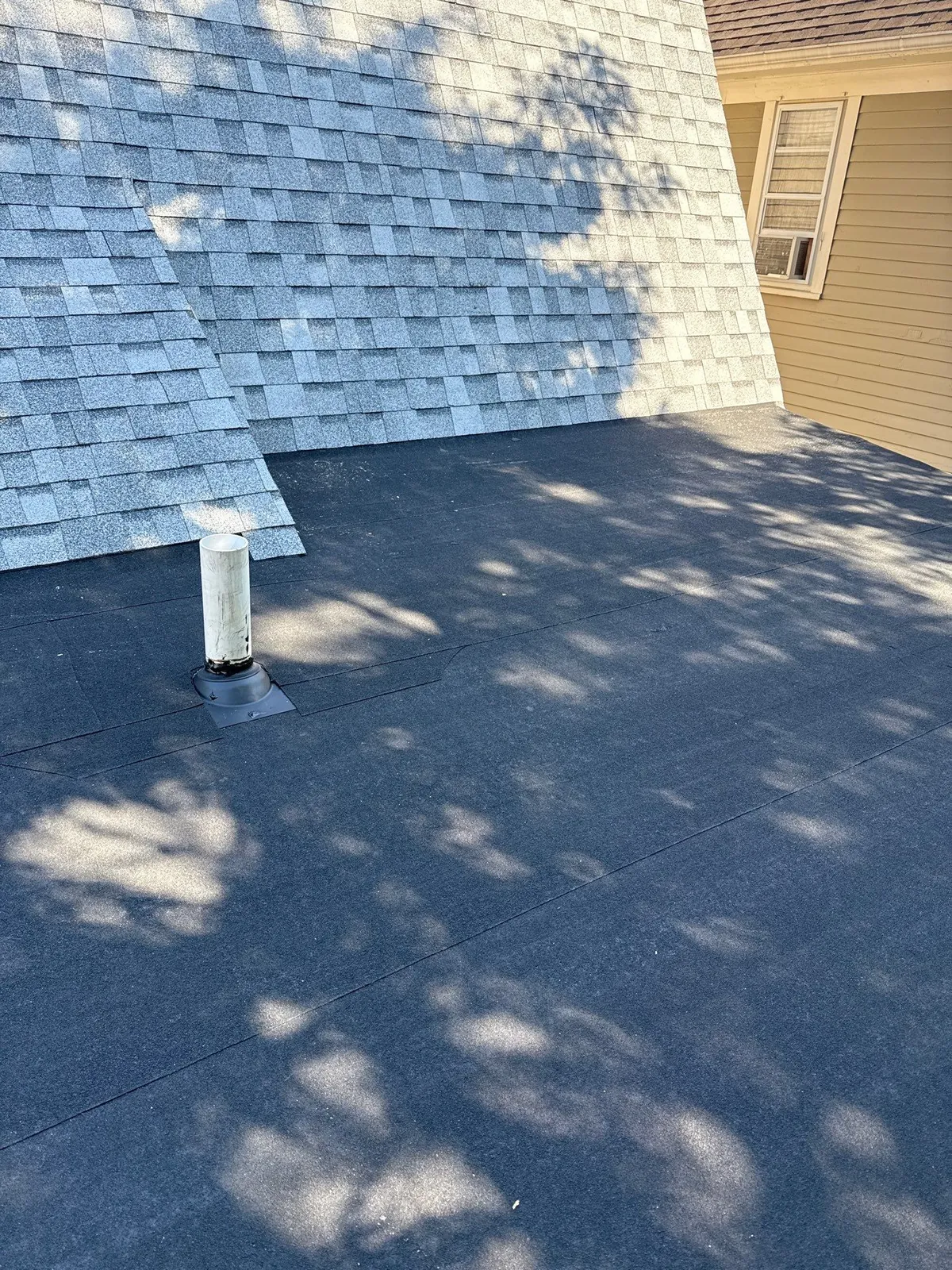 New dark flat roof section meeting a gray shingle roof on a Lakewood, Ohio home
