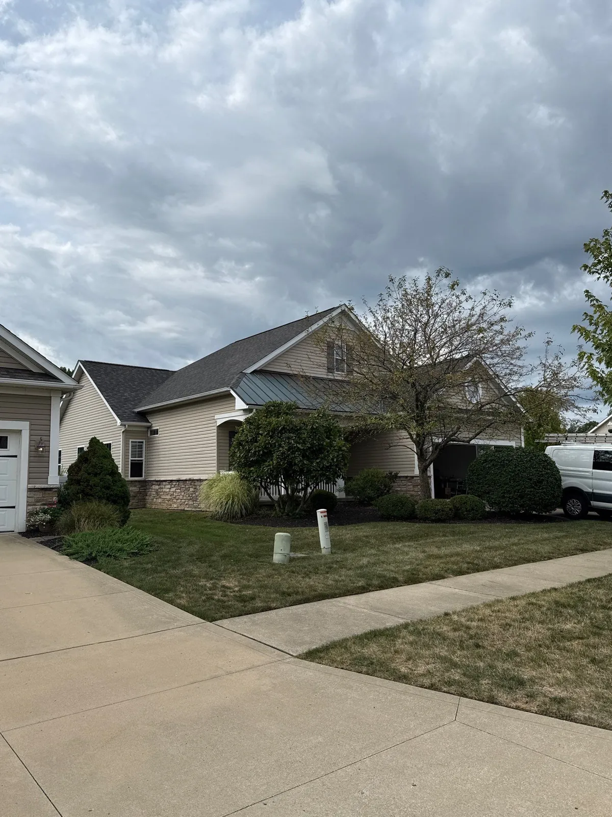 Front view of a tan-sided home with stone accents and a new dark shingle roof in Mentor, Ohio