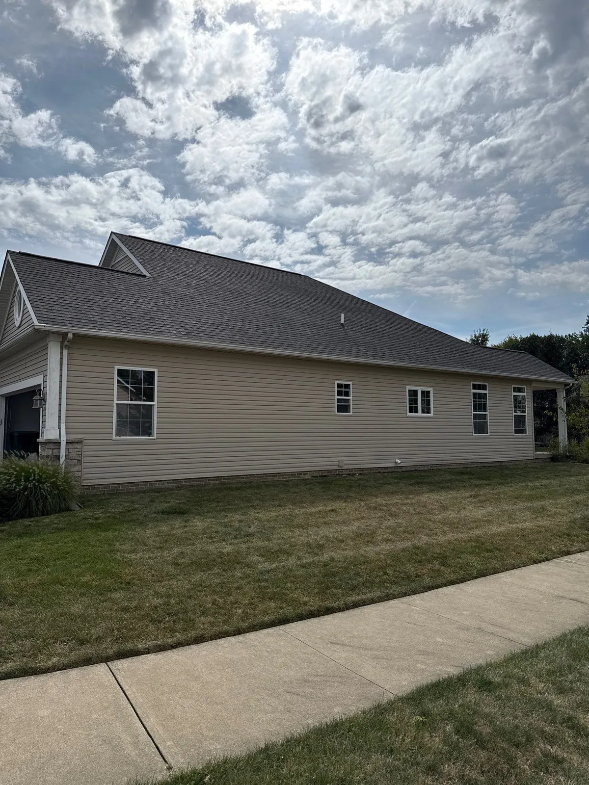 Side view of a tan-sided home in Mentor, Ohio's Newell Creek neighborhood with a new dark shingle roof