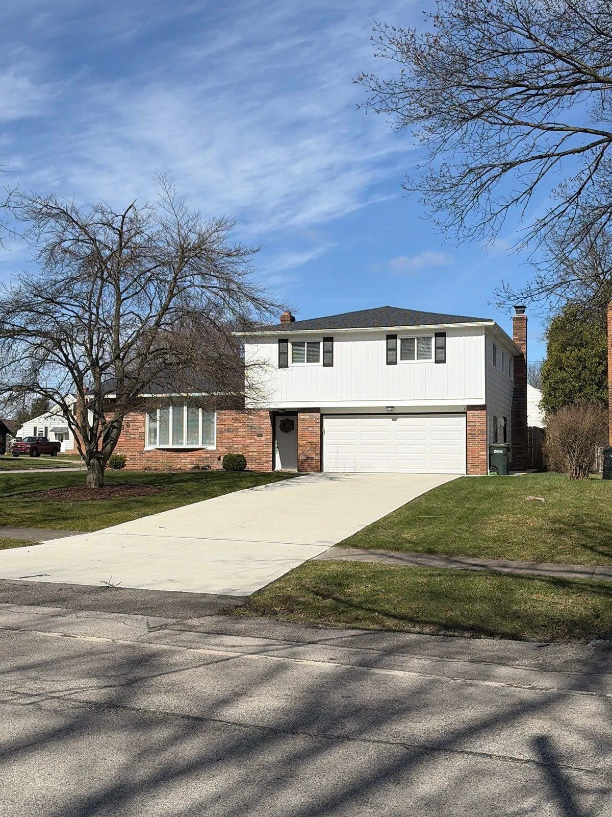 Two-story home with white siding, brick lower level, and a new CertainTeed Landmark Pro Moire Black roof in Middleburg Heights, Ohio