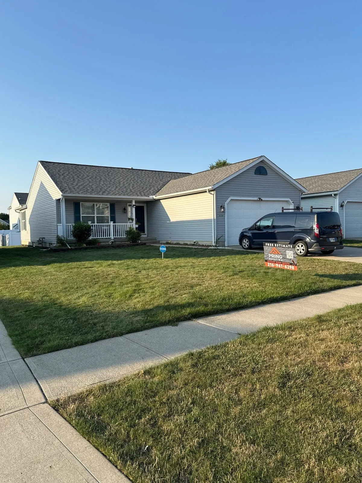 Light gray ranch home with a white porch railing and a new dark shingle roof on a sunny day in North Ridgeville, Ohio