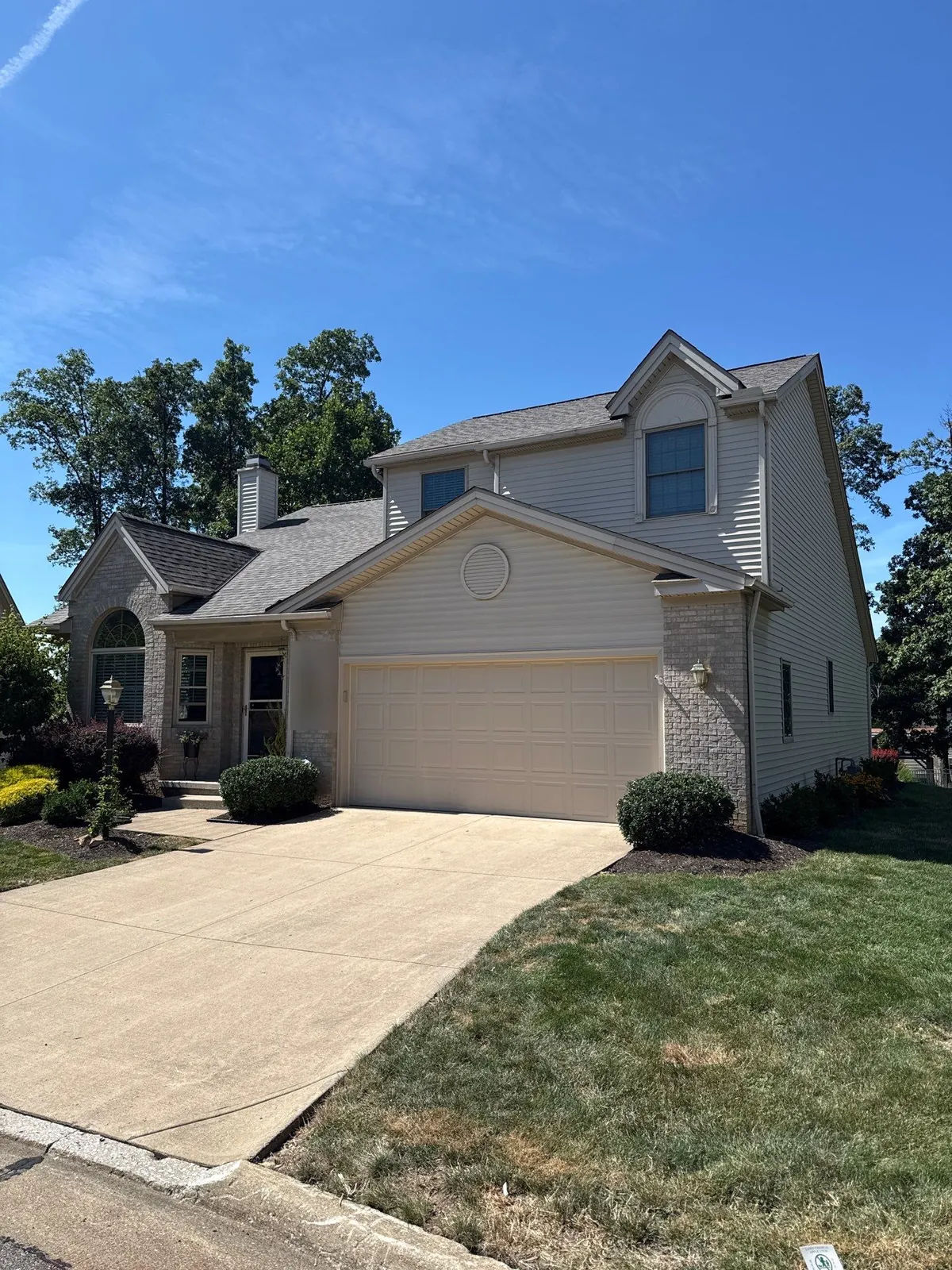 Two-story home with light siding, brick accents, and a two-car garage in North Royalton, Ohio after a full shingle roof replacement