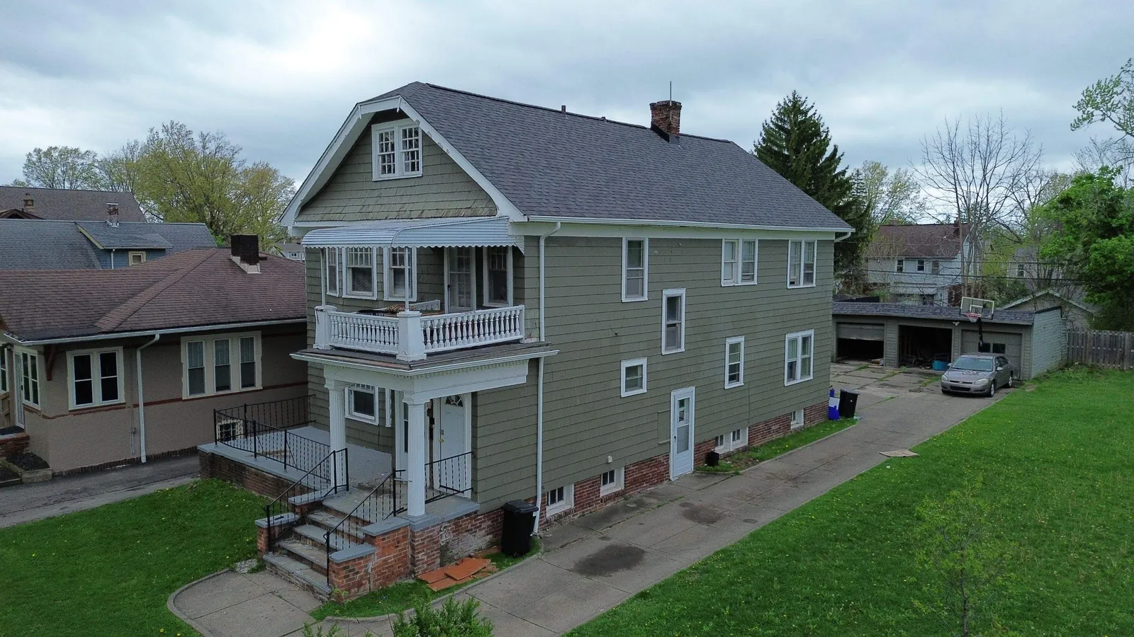 Aerial view of a green-sided two-and-a-half-story home with a new Owens Corning Williamsburg Gray roof and back porches in Shaker Heights, Ohio