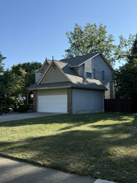 Side view of a two-story Willoughby, OH home with gray siding, decorative gable trim, and a new shingle roof over the attached two-car garage